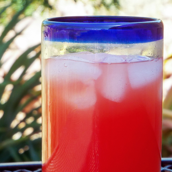 Glass of watermelon agua fresca with lemon served over ice.