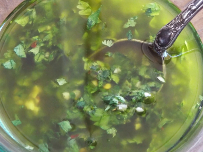 Chimichurri in a glass bowl with a vintage serving spoon.